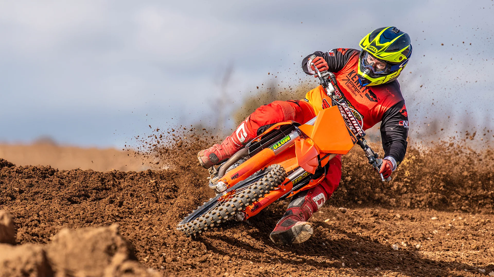 Motocross rider on orange bike kicking up dirt at DMP track